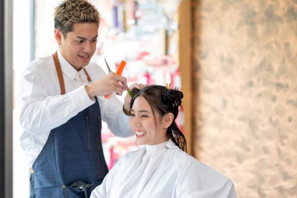 Beautiful Asian woman sit and smile in beauty salon shop that take care of hair cut