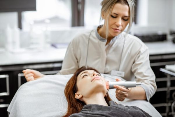 Cosmetologist making facial treatment to a woman