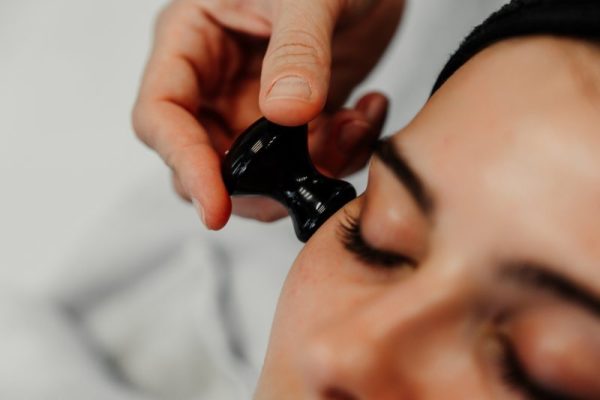 Facial treatment using a black massage tool for relaxation and rejuvenation