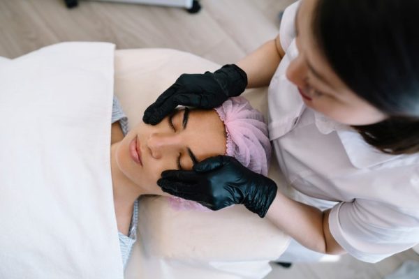 Female specialist doing facial massage to woman