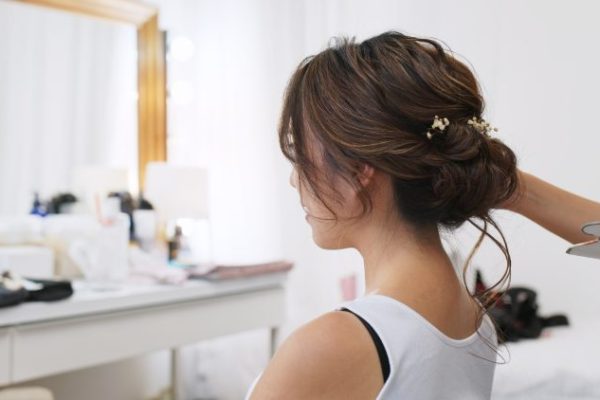 Hairdresser creating a hairstyle for bride in salon