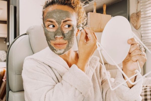 One pretty adult young woman busy in daily skin face care routine using natural green mask