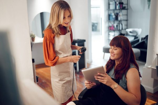 Tablet, salon hairdresser and customer show hairstylist hair cut idea on digital device. Happy woma