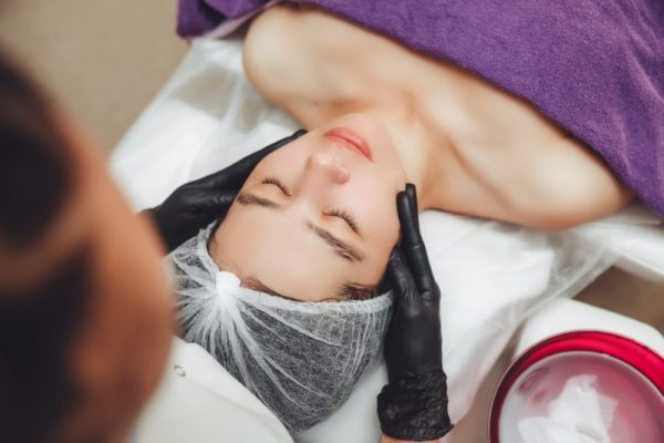 The cosmetologist's hands do a manual relaxing rejuvenating facial massage for a young woman